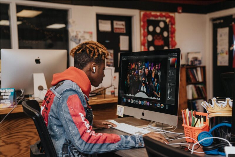 A teen boy works on a computer in a classroom setting